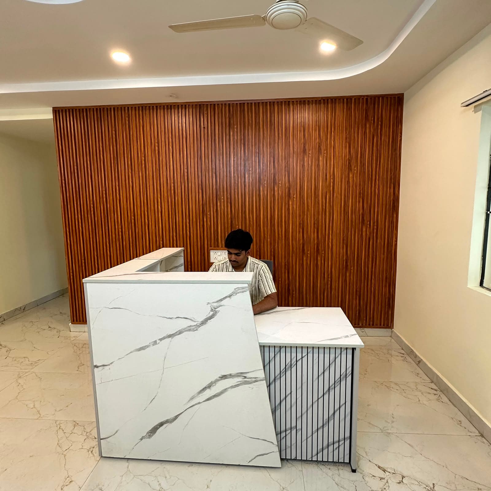 Reception desk at Hitex Health Nest, backed by a full-height wooden slat wall